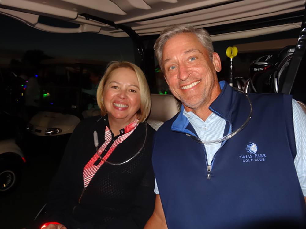 A couple smiles on a golf cart